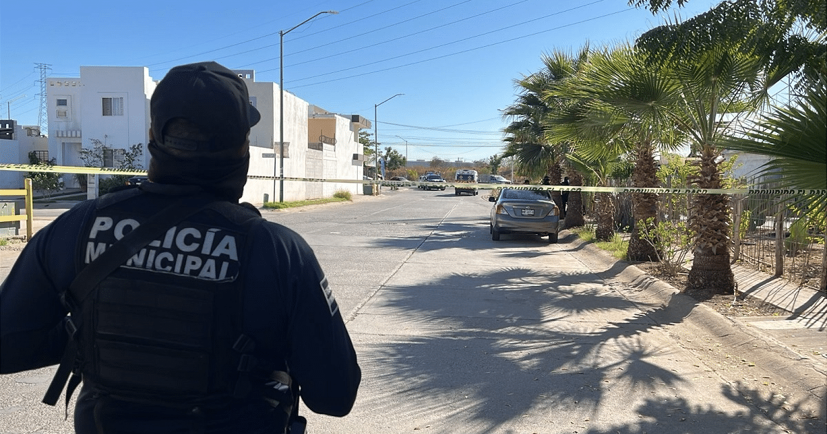 Oficial de policía en escena de accidente de tránsito en Guasave, con cinta amarilla y vehículos de emergencia.