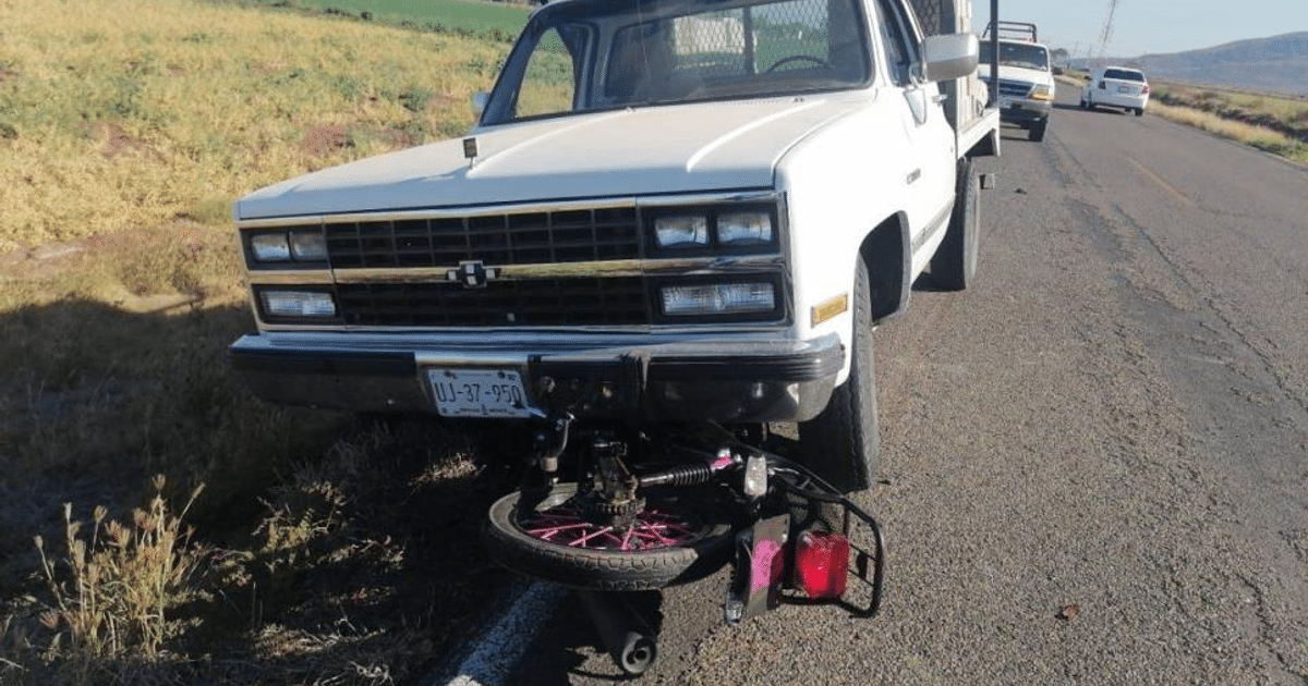 Accidente entre Chevrolet Custom blanco y motocicleta Italika rosa en carretera rural