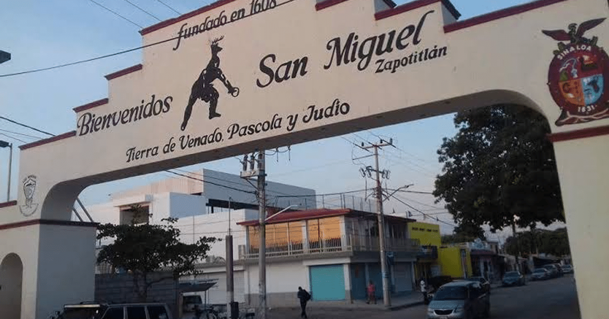 Arco de bienvenida a San Miguel Zapotitlán con inscripciones históricas y fondo urbano.