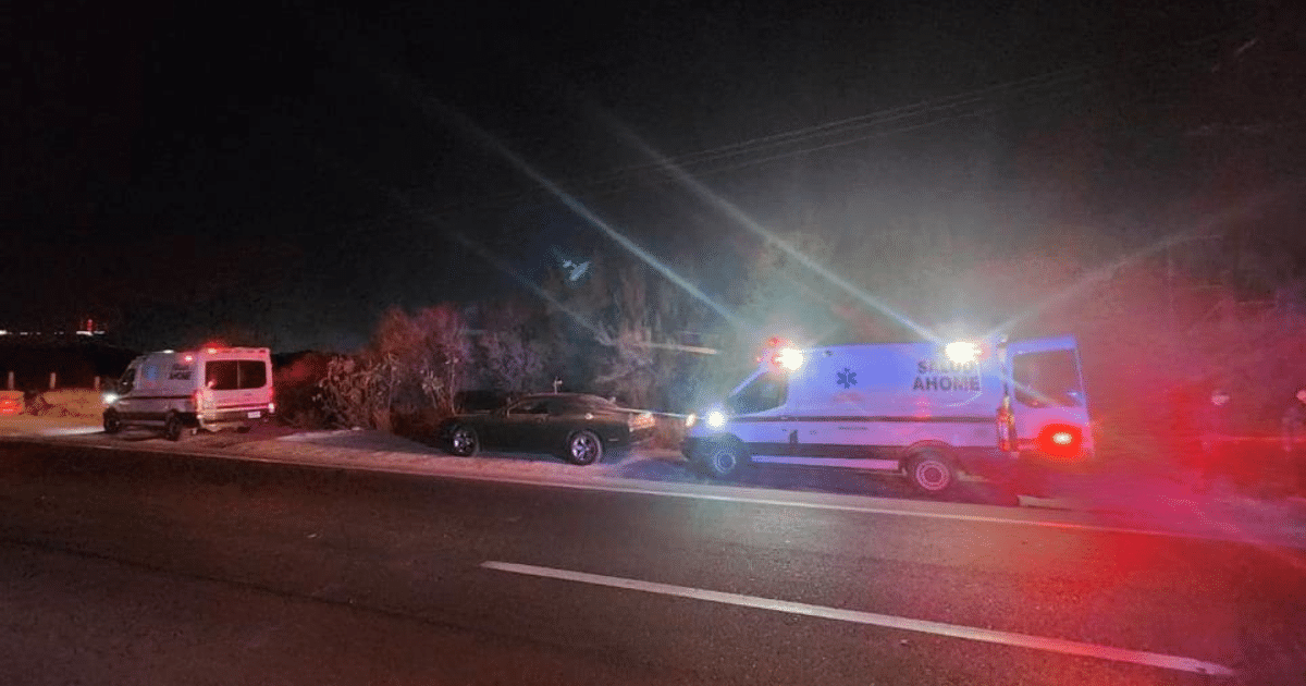 Ambulancia con luces encendidas en la carretera durante la noche, indicando un posible accidente o emergencia.