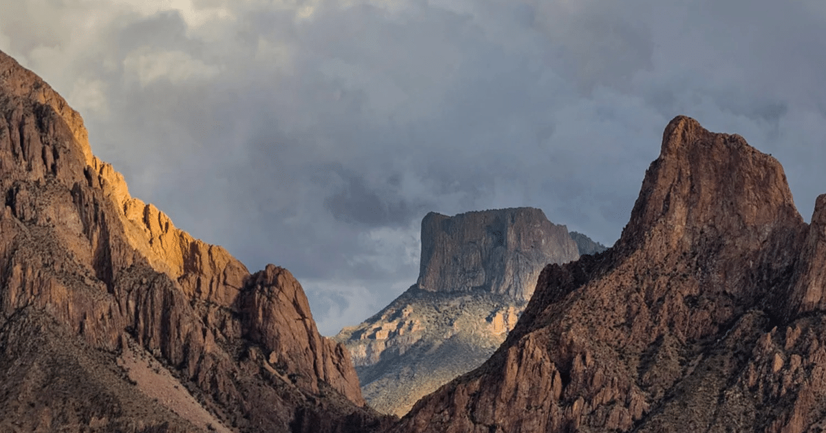 Paisaje montañoso con formaciones rocosas y picos prominentes bajo un cielo nublado.