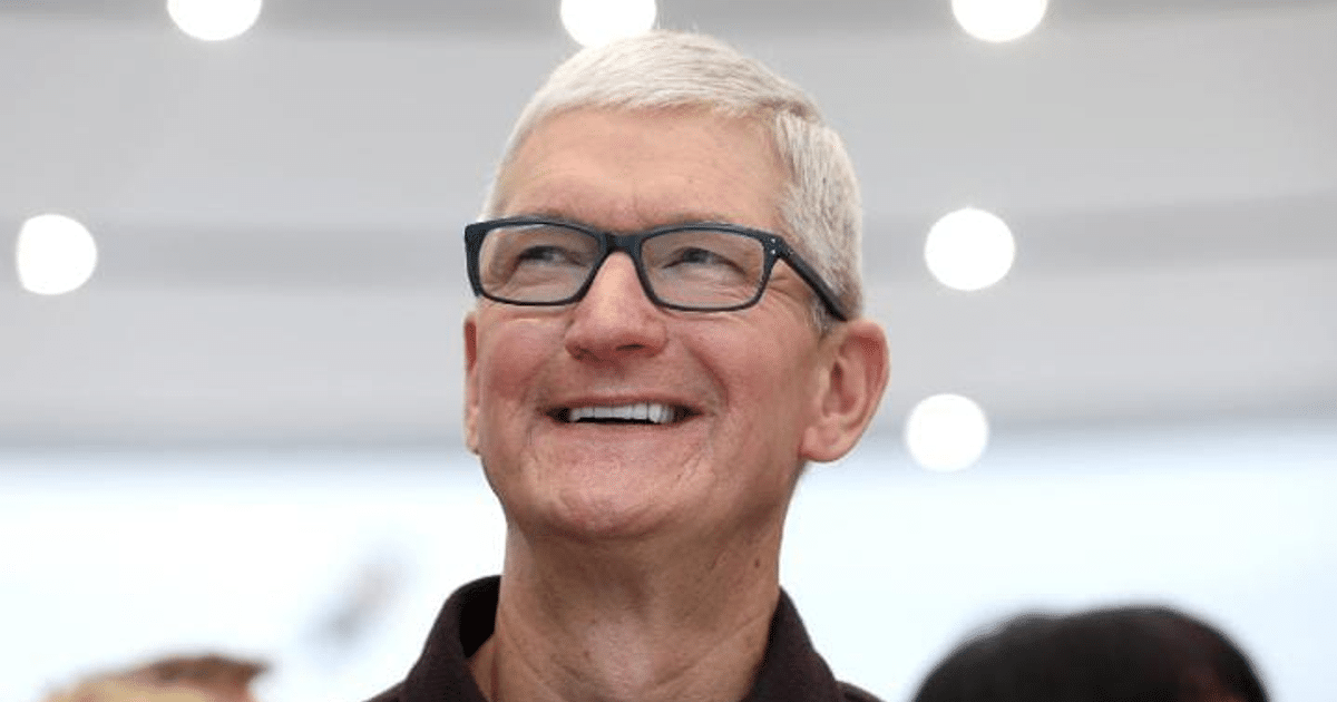 Persona sonriendo en un entorno iluminado durante la reunión en Washington sobre inversiones de Apple.