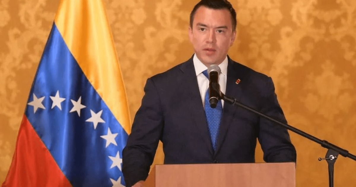 Presidente de Ecuador Daniel Noboa hablando frente a un micrófono con la bandera de Venezuela detrás.