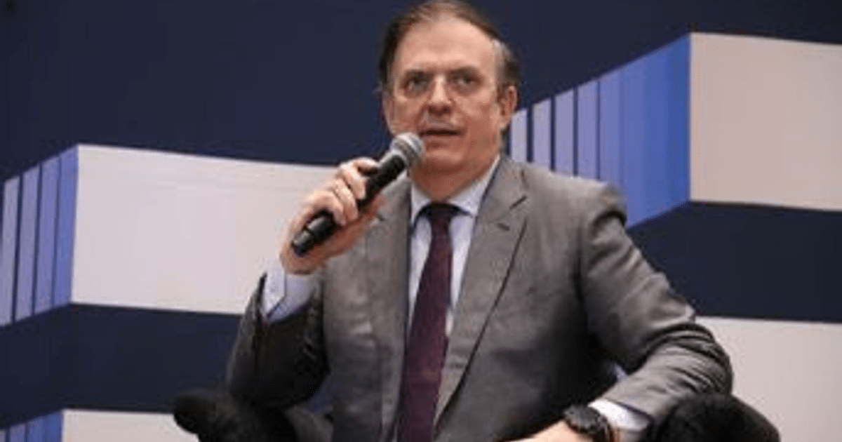 Hombre en traje con micrófono durante una conferencia sobre acuerdos comerciales.