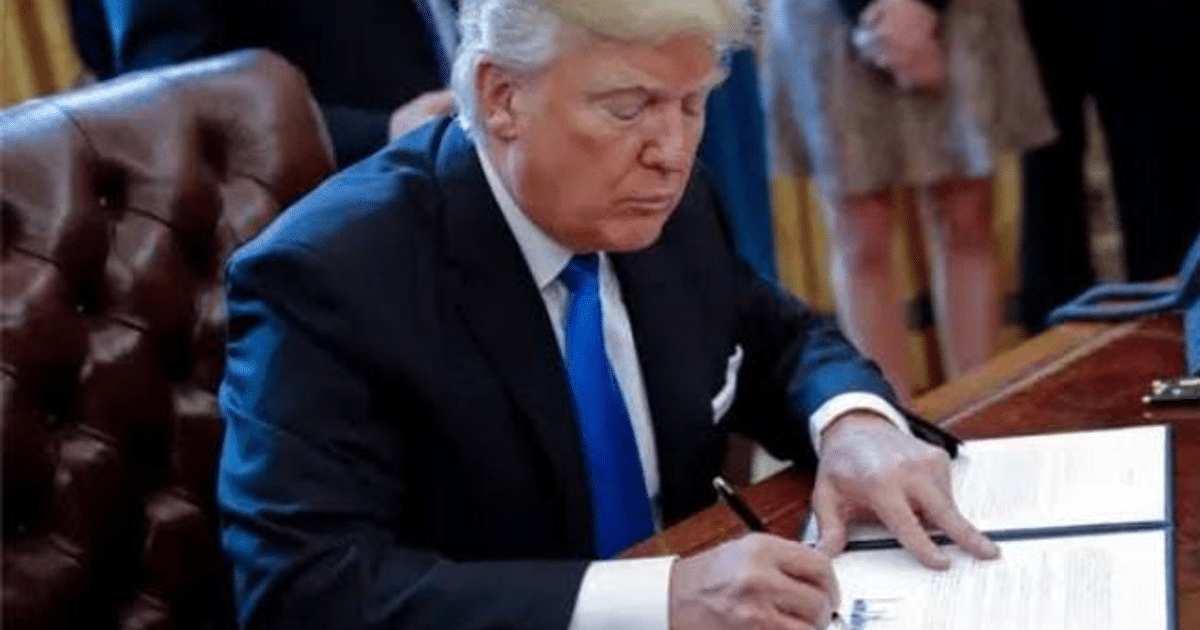 Funcionario en traje oscuro firmando documento en la Oficina Oval, relacionado con aranceles recíprocos.