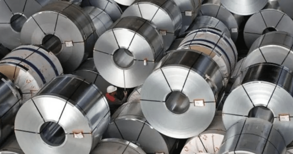 Bobinas de metal apiladas en un entorno industrial con una persona usando casco, relacionadas con aranceles recíprocos en EE.UU.