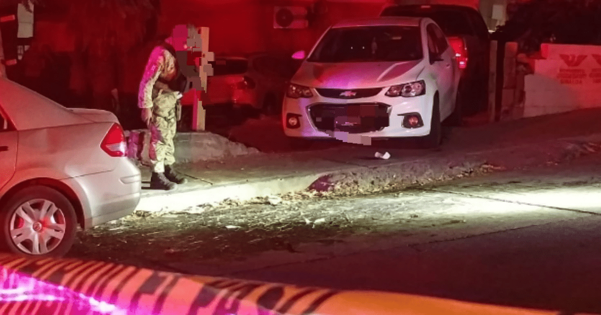 Soldado en uniforme militar en una calle nocturna de Culiacán, cerca de un coche blanco y luces brillantes, en un área restringida.