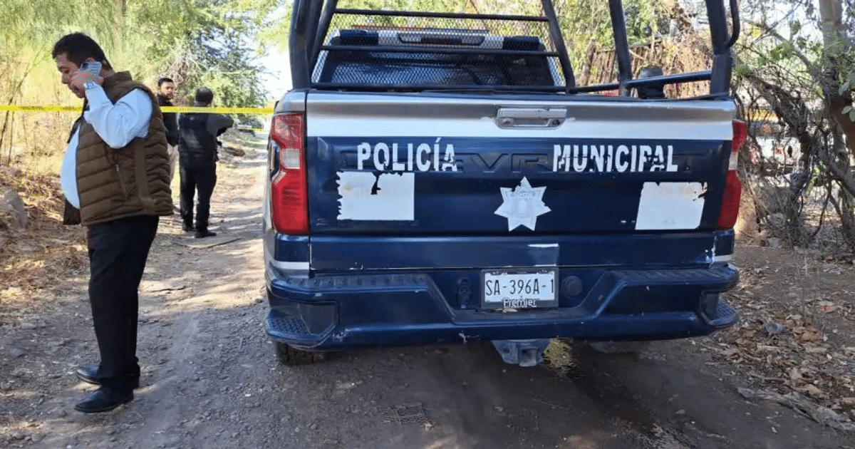 Camioneta de policía en escena de crimen con cinta amarilla y hombre al teléfono en Culiacán.
