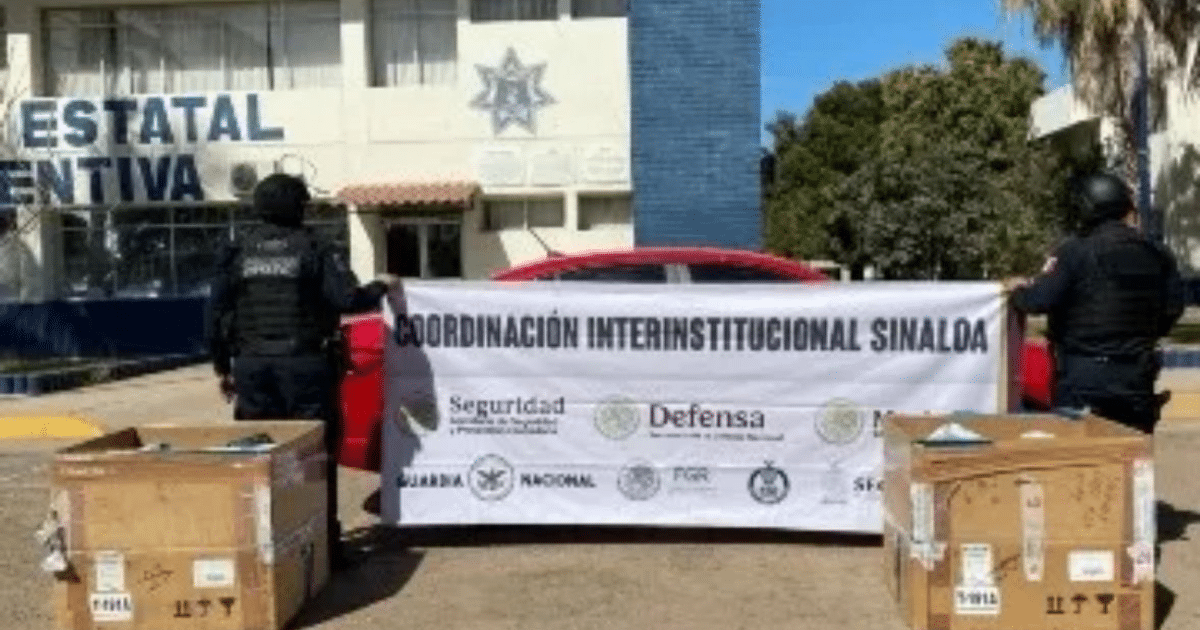 Dos personas con chalecos de seguridad sostienen un cartel de coordinación interinstitucional en Sinaloa, en un evento de seguridad pública.