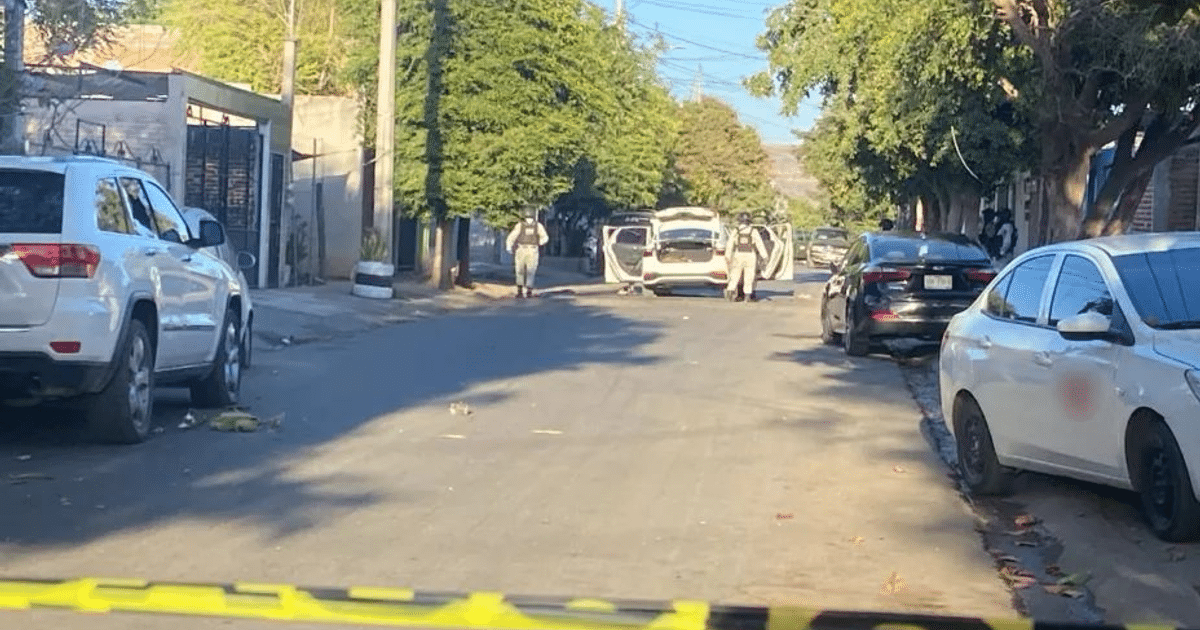 Calle en Culiacán con vehículos estacionados y agentes de seguridad, zona acordonada con cinta amarilla.