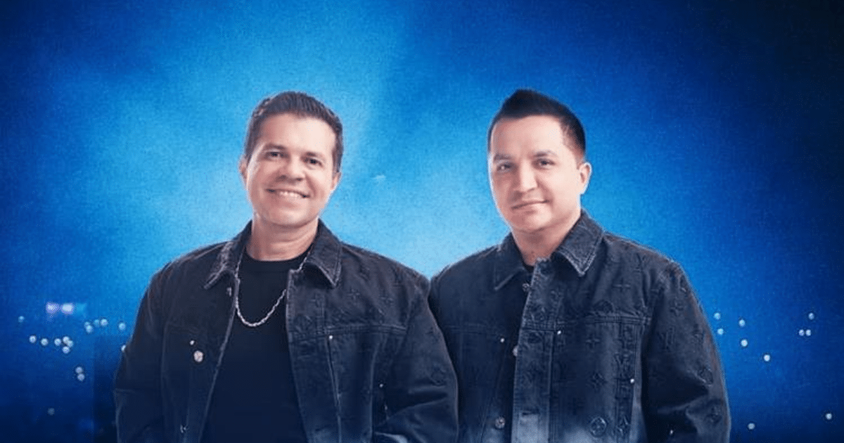 Josi Cuen y Jorge Medina del dúo 'Juntos' sonriendo en chaquetas de mezclilla frente a un fondo azul.