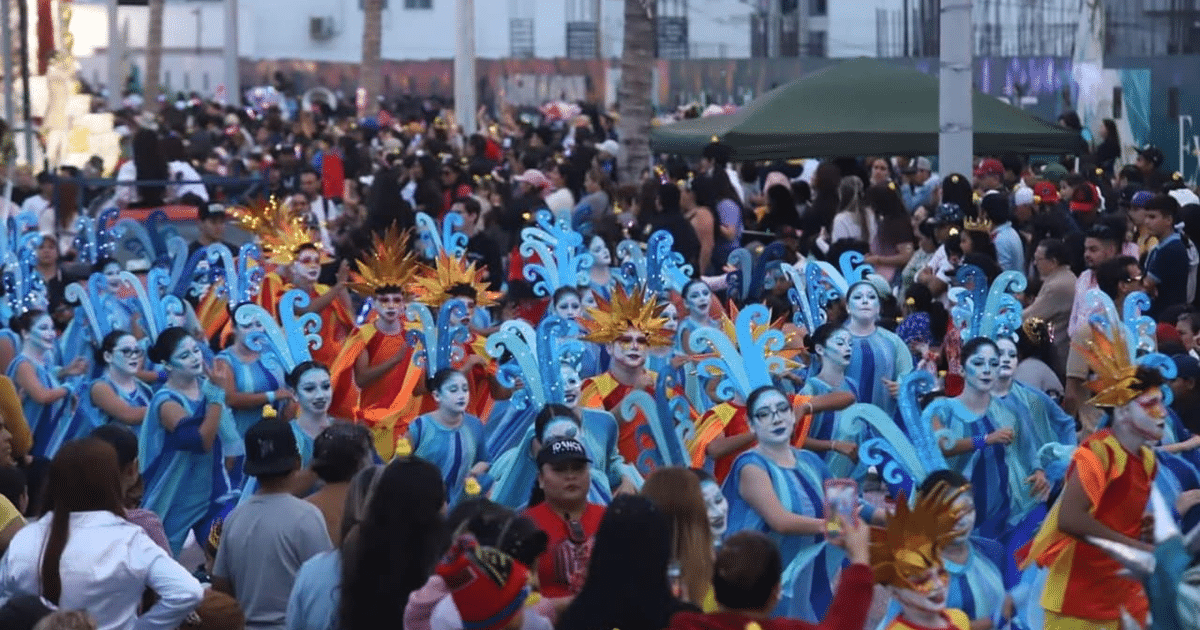 Multitud en el Carnaval Internacional de Mazatlán con trajes coloridos y pinturas faciales.