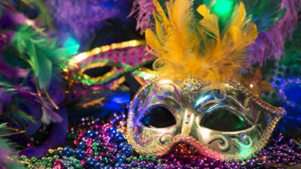 Máscara de carnaval con plumas amarillas y cuentas de colores sobre un fondo festivo.