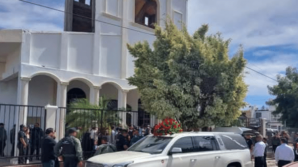 Ceremonia de homenaje en la parroquia de San Pablo Apóstol con vehículo adornado y asistentes formales.