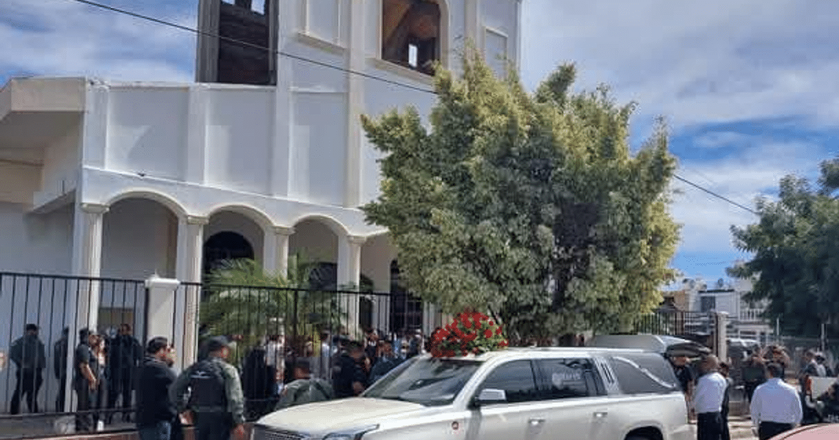 Ceremonia de homenaje en la parroquia de San Pablo Apóstol con vehículo adornado y asistentes formales.