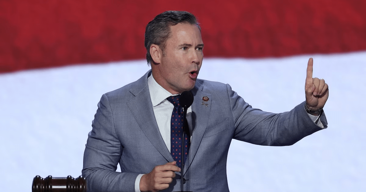 Mike Waltz hablando en un evento político con traje claro y corbata de puntos.