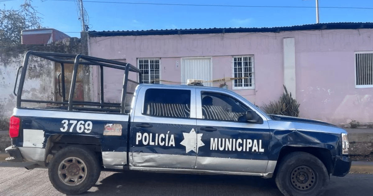 Camioneta de Policía Municipal dañada frente a edificio rosa en Culiacán, con cinta amarilla de seguridad.