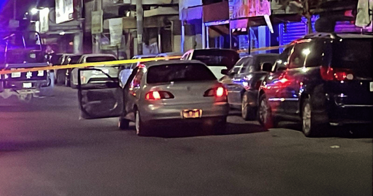 Calle urbana nocturna con automóvil gris y cinta amarilla de acordonamiento en Culiacán.