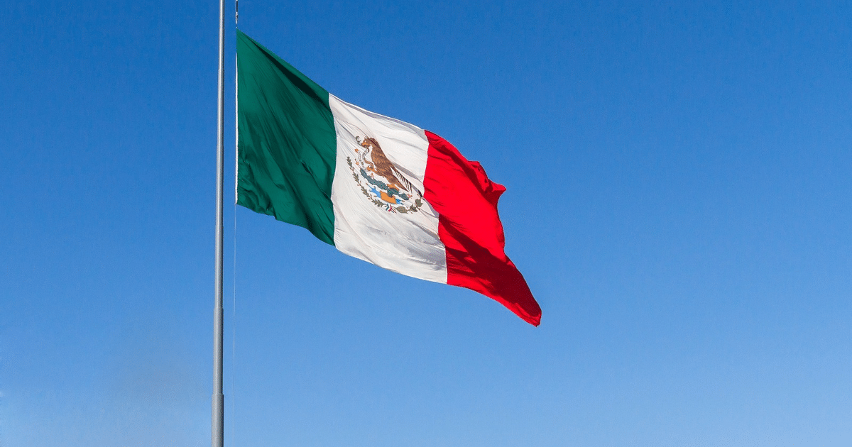 Bandera de México ondeando con cielo azul de fondo