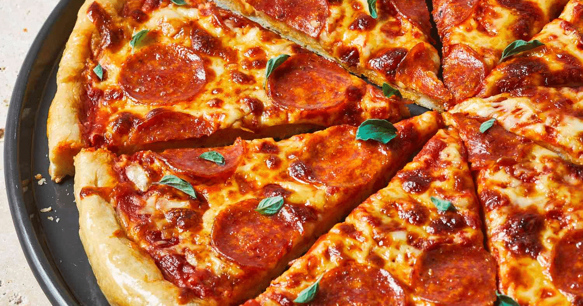 Pizza de pepperoni con hojas verdes, queso derretido y salsa de tomate sobre base crujiente.