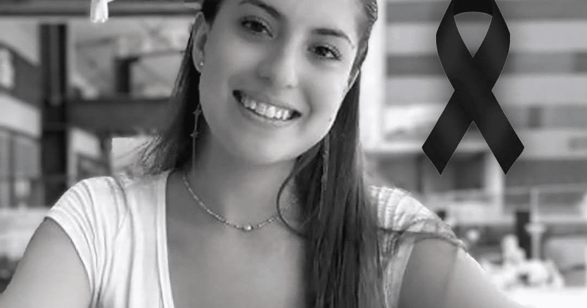 Mujer sonriendo con lazo negro de luto, fondo interior desenfocado.