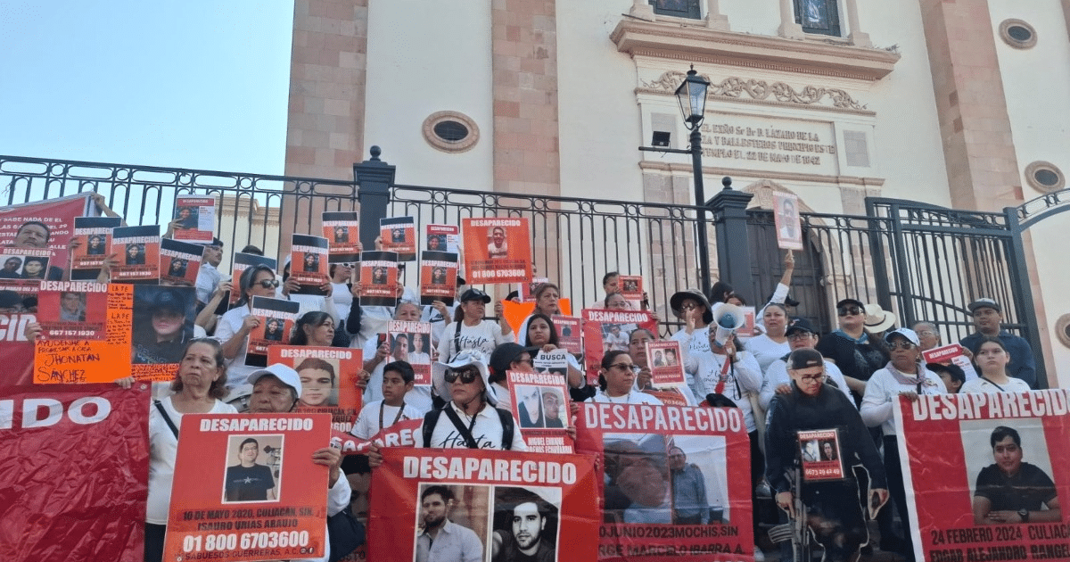 Grupo de personas en Sinaloa protestando por desaparecidos, sosteniendo carteles y fotos.