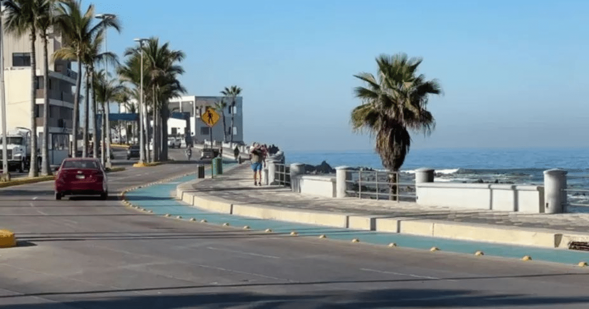 Paseo marítimo en Mazatlán con coche rojo, palmeras y océano en un día soleado