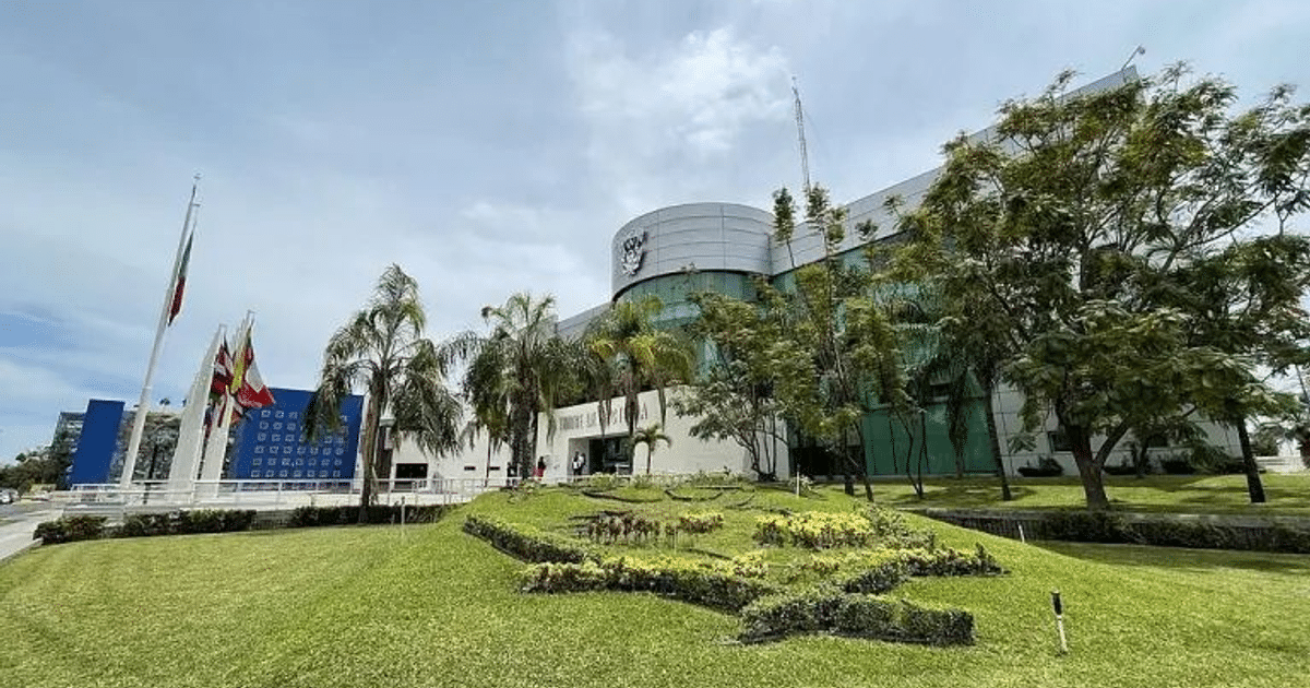 Edificio moderno de la Universidad Autónoma de Sinaloa con banderas ondeando al frente.