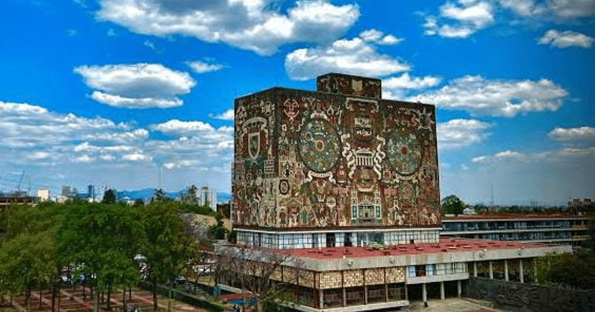 Edificio educativo con murales coloridos, árboles y cielo nublado, relacionado con el examen en línea de UNAM e IPN.