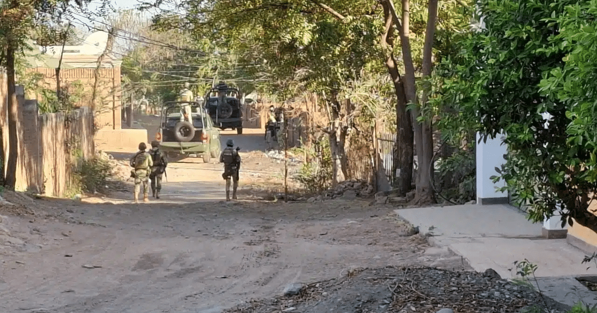 Soldados armados caminando hacia vehículos militares en un camino de tierra, rodeados de árboles, en respuesta a la explosión en Culiacán.