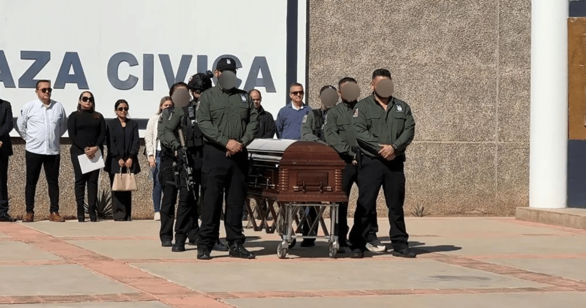 Ceremonia de homenaje en Plaza Cívica con ataúd marrón y asistentes formales y uniformados.