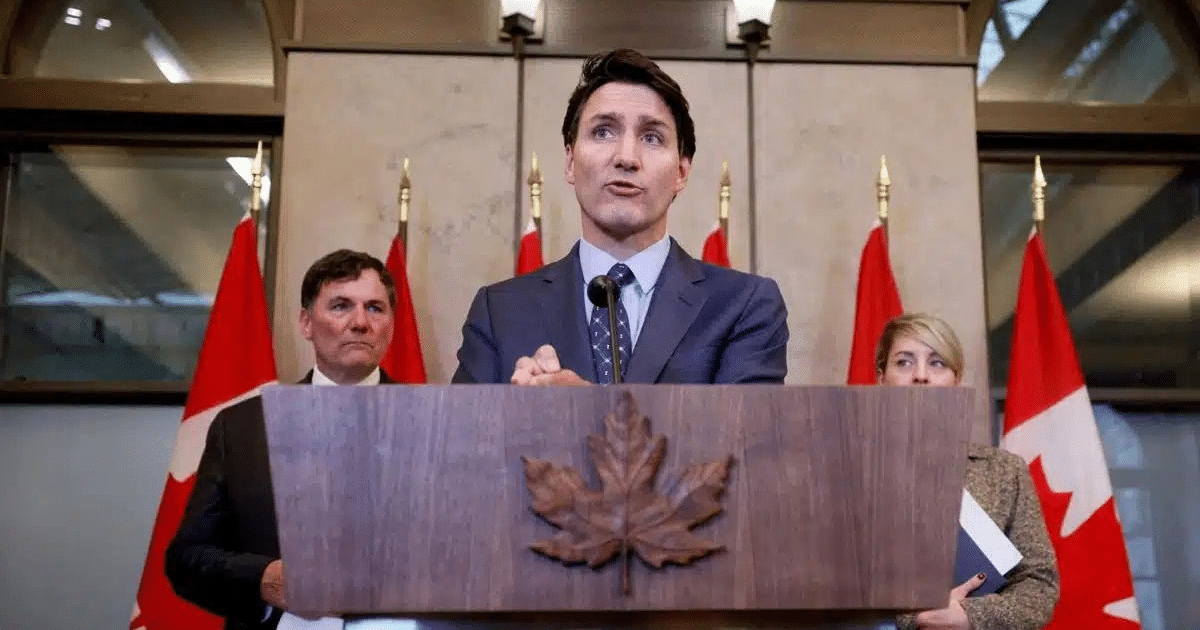 Kevin Brosseau en un podio con banderas canadienses, hablando sobre el tráfico de fentanilo.