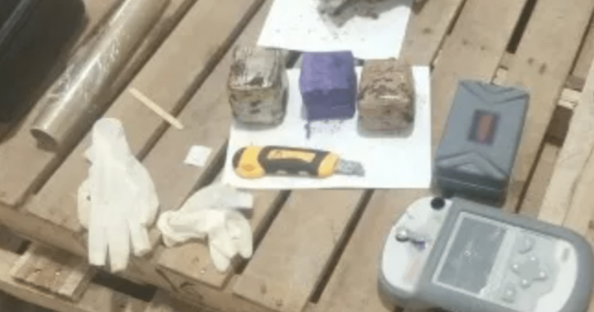 Herramientas de inspección en aeropuertos sobre una mesa de madera, incluyendo guantes, cuchillo, bloques, medidor, tubo y palito.