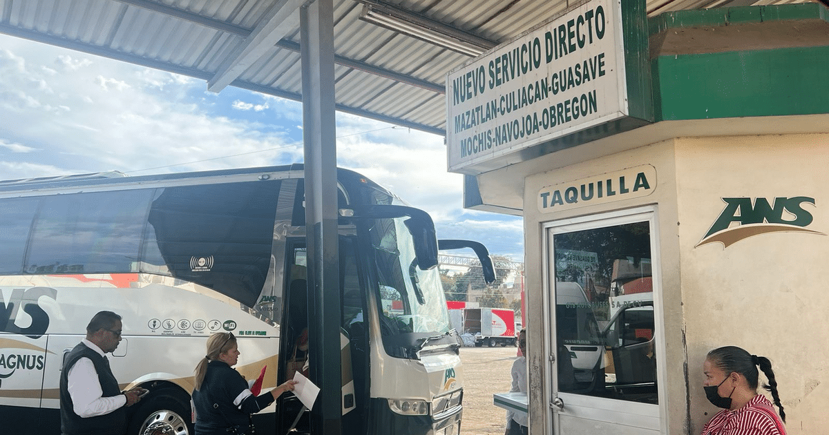 Autobús de ANS en terminal con quiosco de taquilla y letrero de nuevo servicio directo a varios destinos.
