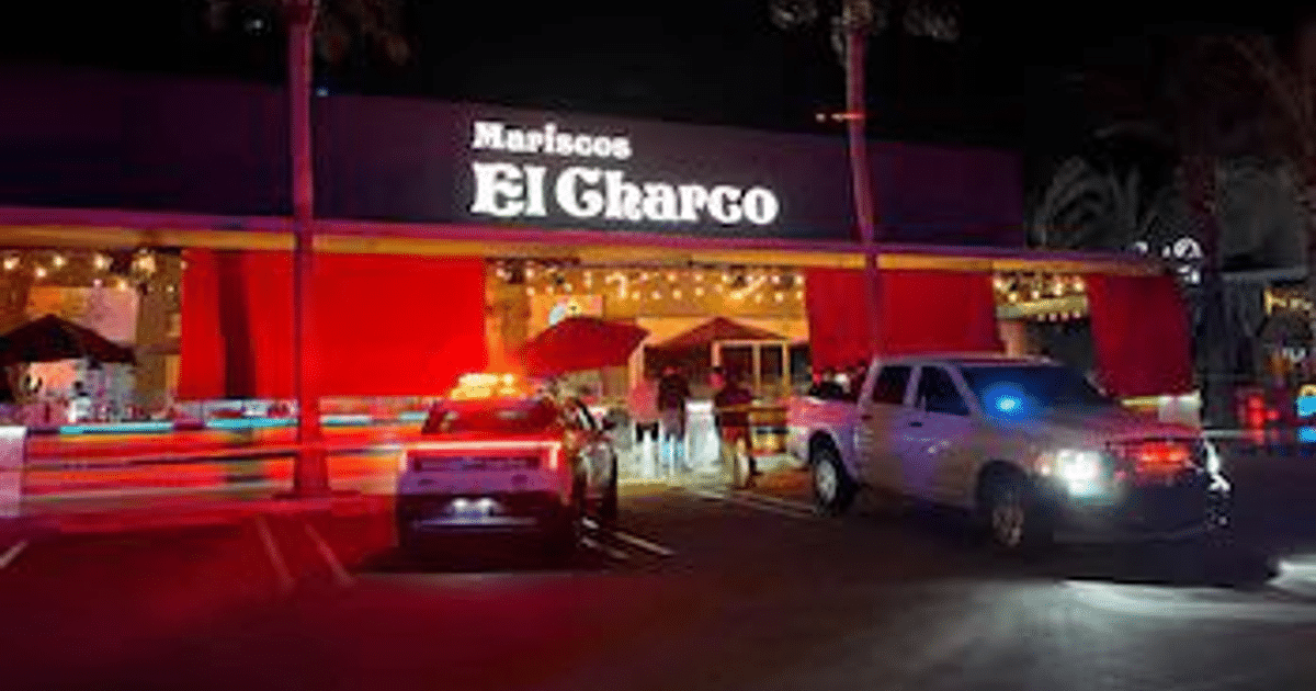 Restaurante Mariscos El Ghargo iluminado de noche con vehículos y personas en la entrada