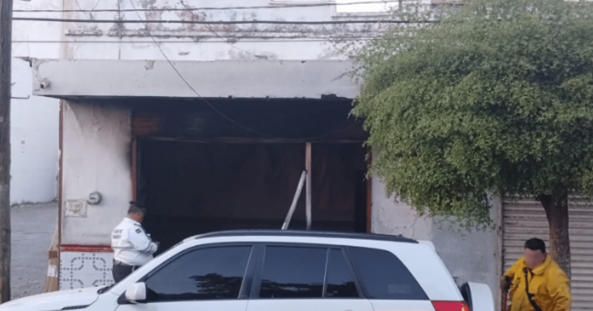 Local comercial en Culiacán tras incendio, con auto blanco y personas en ropa de trabajo.