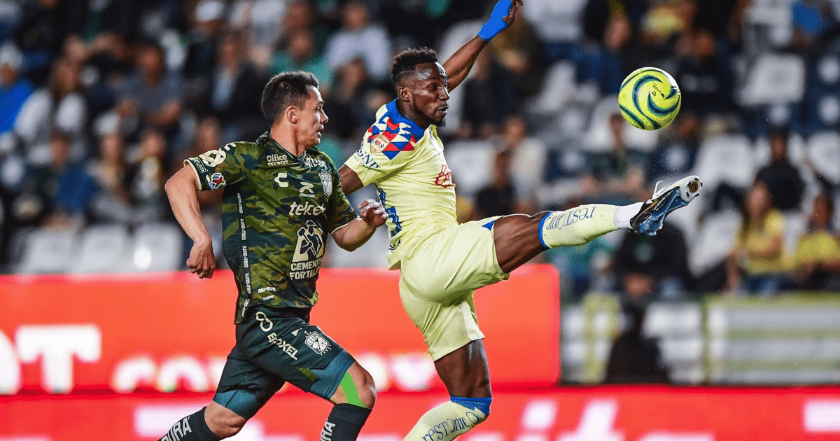 Dos jugadores de fútbol en acción durante el partido América vs León, uno con uniforme amarillo y otro con uniforme verde, en un estadio lleno de espectadores.