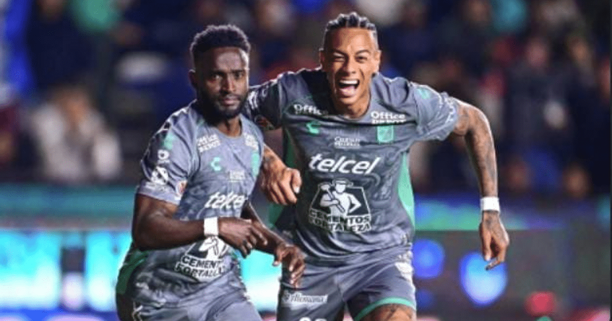 Dos futbolistas de León celebrando un gol en el Estadio Hidalgo, vistiendo camisetas grises con detalles verdes.
