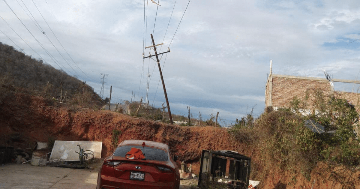 Coche rojo en entorno semiurbano de Mazatlán con cielo nublado y elementos urbanos.