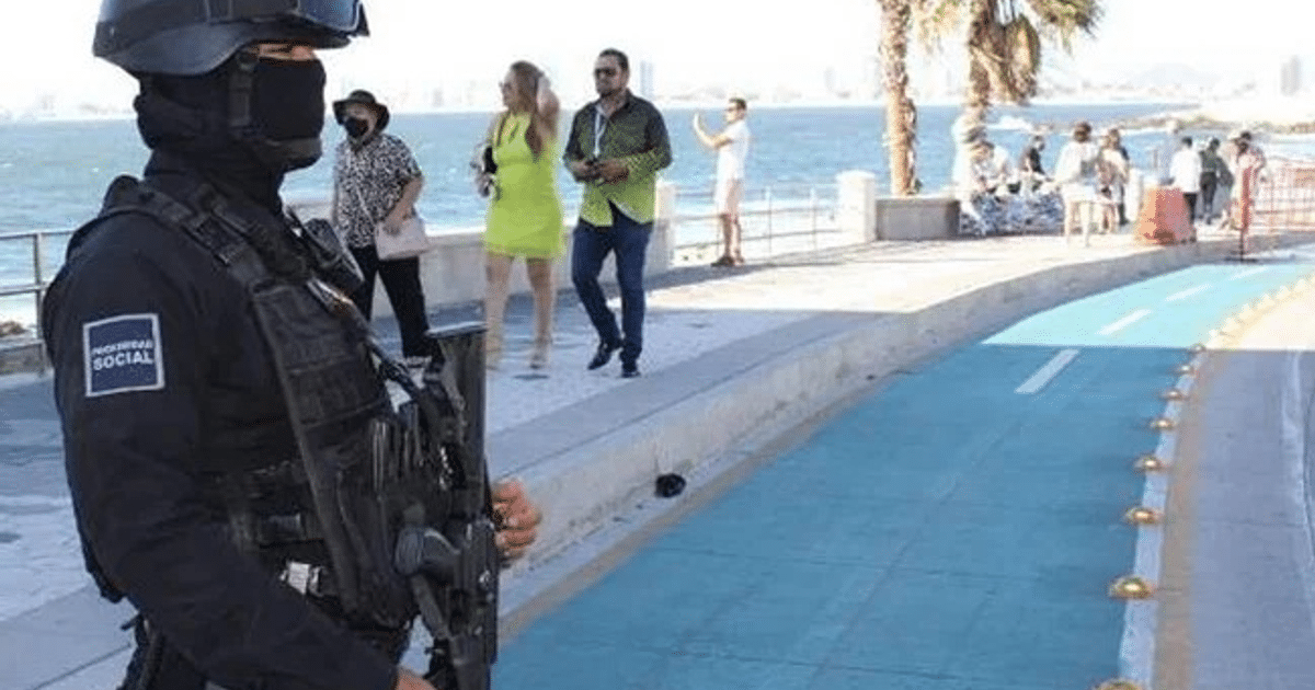 Policía en uniforme táctico en Mazatlán, con personas y mar de fondo