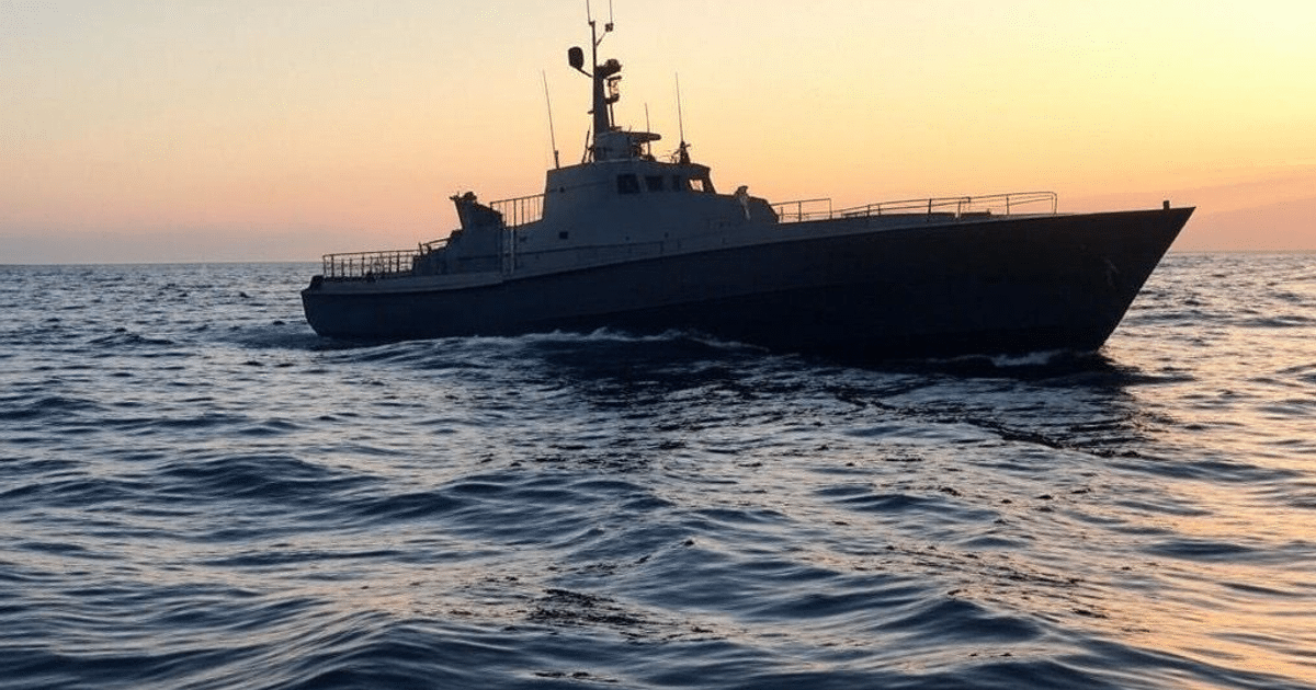 Barco de patrullaje en el mar al atardecer con cielo naranja y azul
