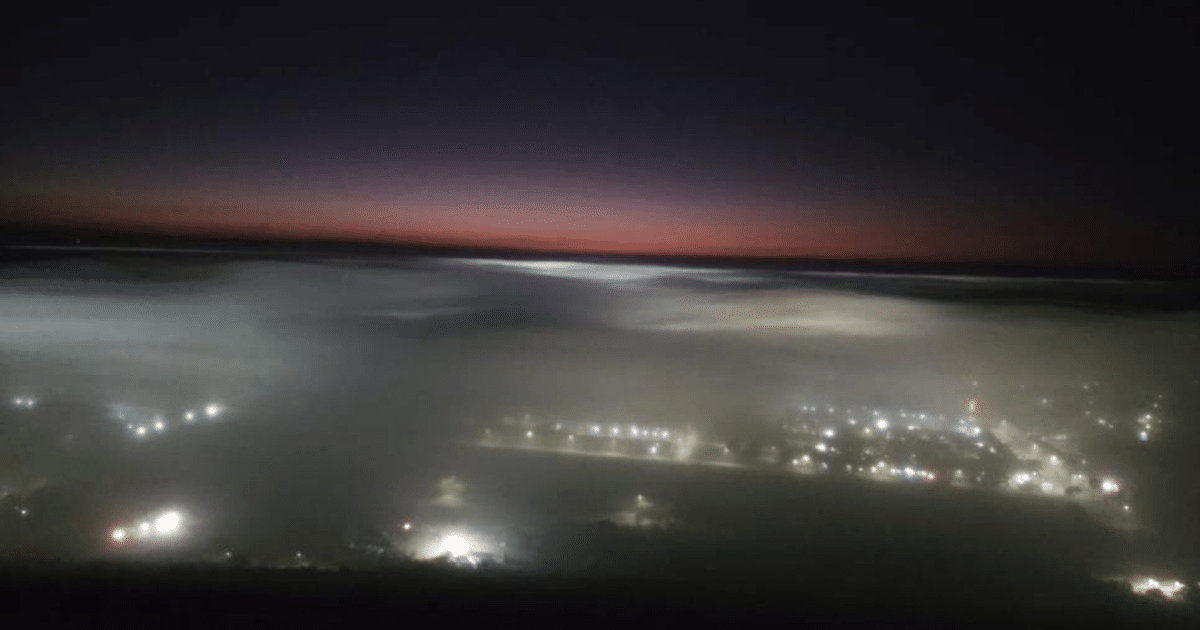 Escena nocturna con niebla densa y luces urbanas en Sinaloa
