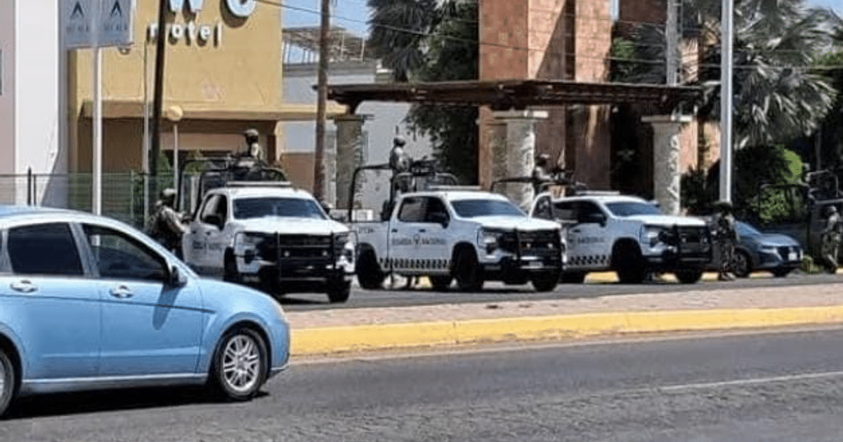 Camionetas de policía estacionadas en carretera durante operativo en Culiacán, con agentes de seguridad visibles y un coche azul en primer plano.
