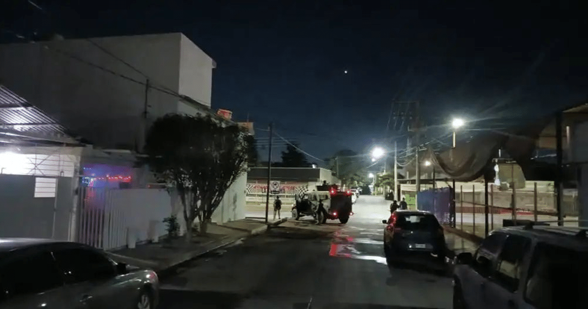 Calle nocturna en Culiacán con vehículos y personas durante un operativo militar.