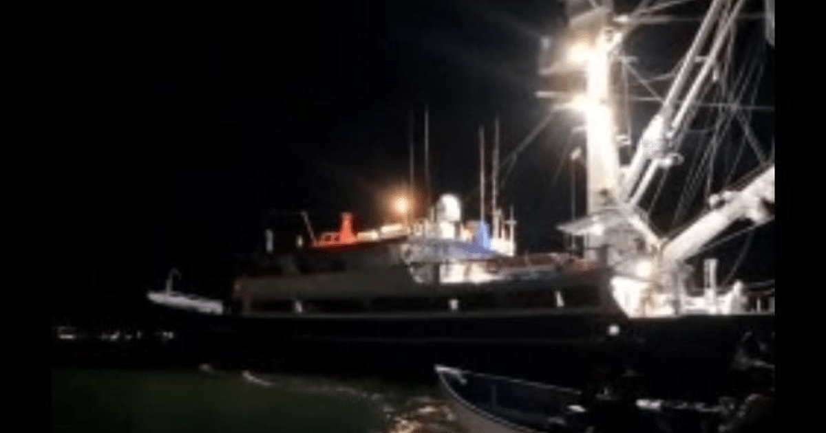 Barco iluminado en la noche con luces brillantes y equipos visibles en la parte superior