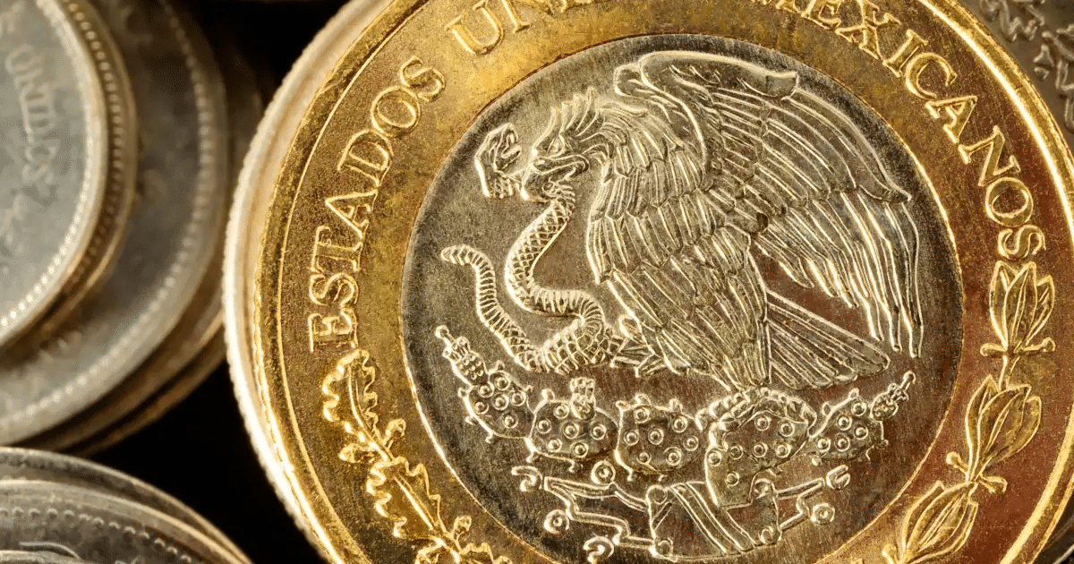 Moneda mexicana con águila nacional en primer plano, otras monedas desenfocadas al fondo.