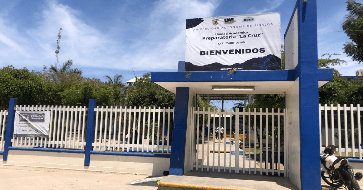 Entrada de la Preparatoria La Cruz de la UAS con cartel de bienvenida y plantas alrededor.