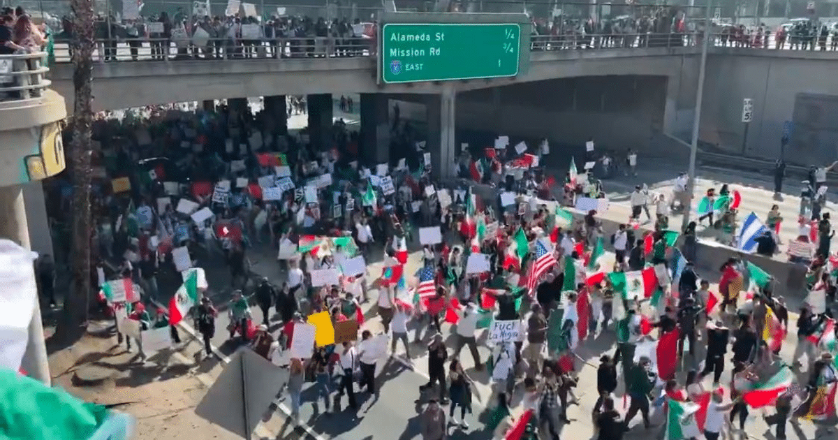 Multitud en manifestación en Los Ángeles con pancartas y banderas de México y EE.UU. cerca de la autopista 101.
