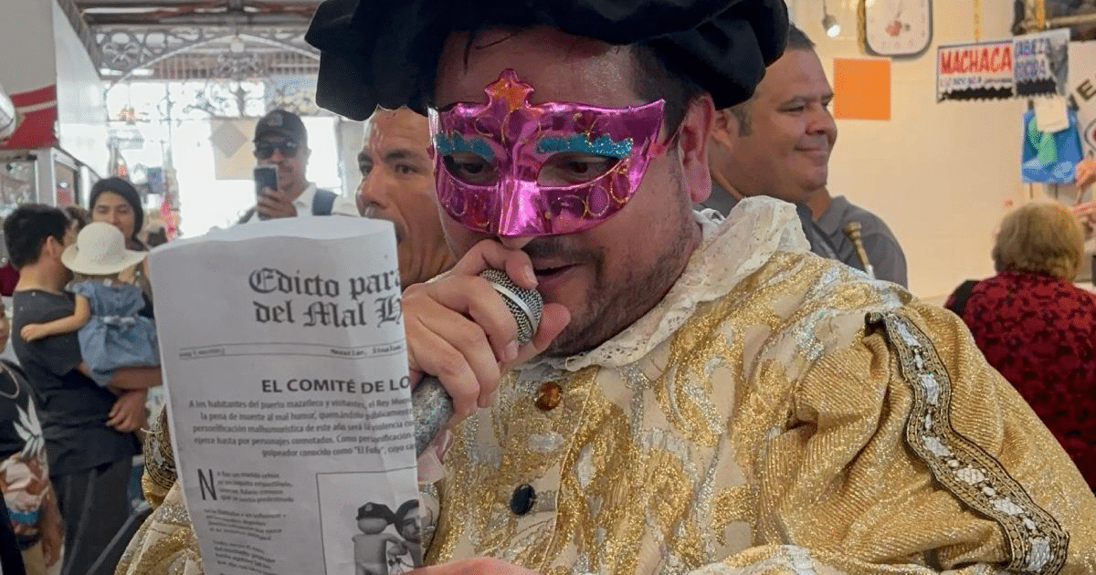 Hombre en traje decorado y máscara rosa anuncia evento en Mazatlán
