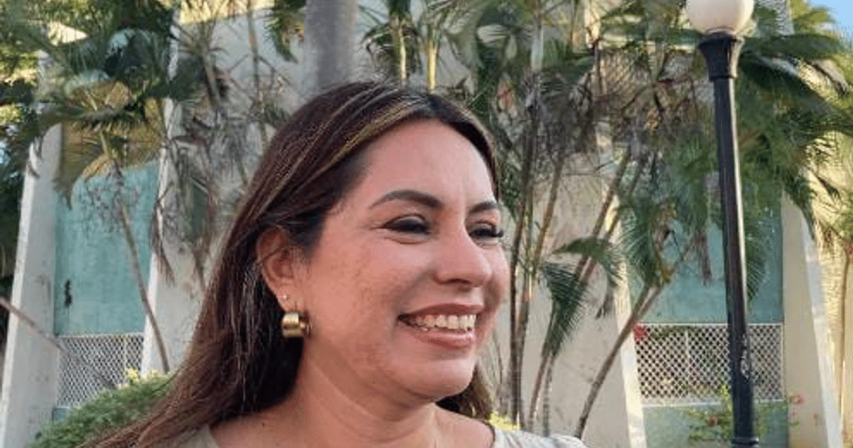 Mujer sonriendo en protesta en Mazatlán con plantas y luminaria de fondo